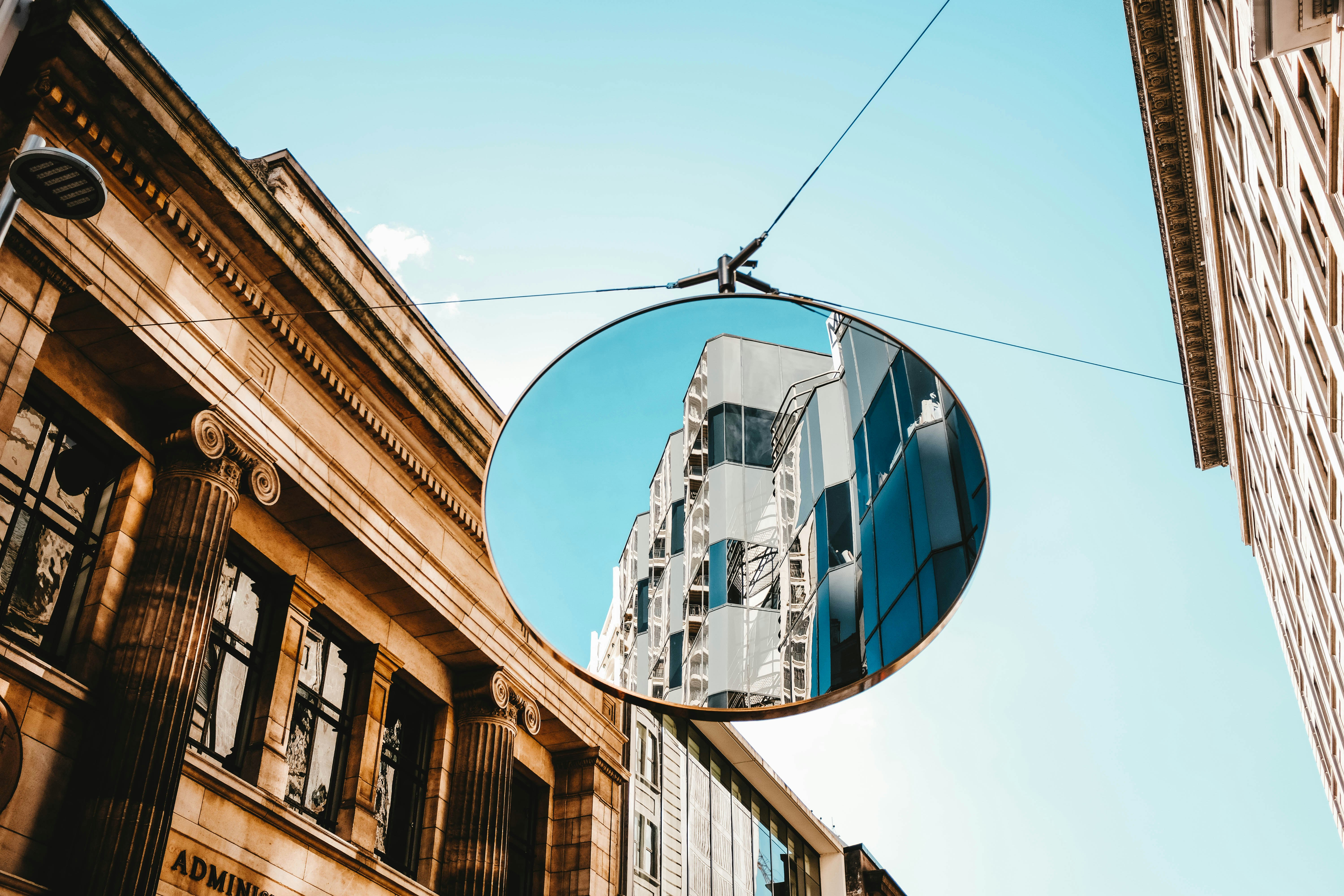round gray framed mirror in middle of buildings